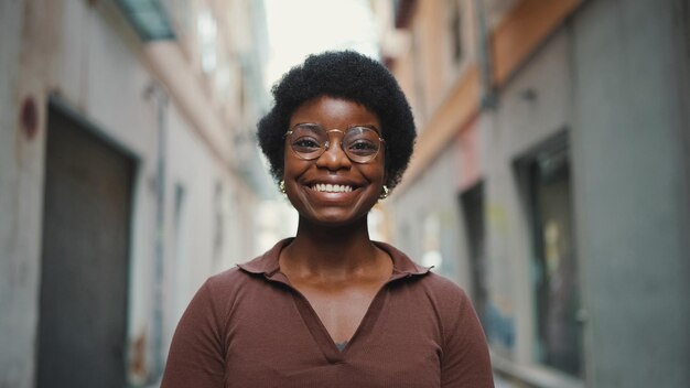 Веселая африканская женщина в очках выглядит счастливой на улице Carefr
