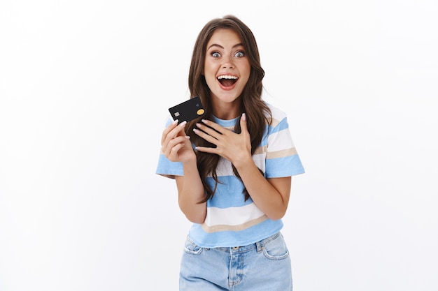 Cheerful amazed good-looking female with credit card, gesturing enthusiastic impressed with awesome banking offer, praying for cashback and cool discounts, paying for online shopping
