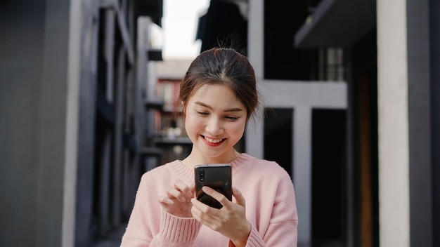 Cheerful Asian backpacker blogger woman using smartphone for direction and looking on location map while traveling at Chinatown in Beijing, China. Lifestyle backpack tourist travel holiday concept.