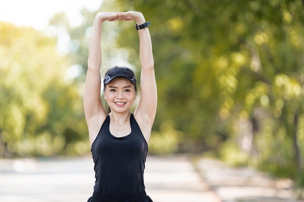 Free photo a cheerful asian female runner in sports outfits doing stretchin