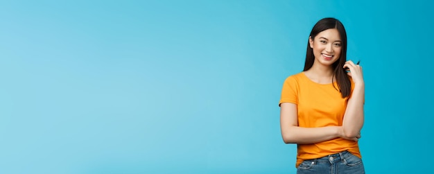 Cheerful asian girl with dark short haircut touching hair strand smiling lively cross one arm chest