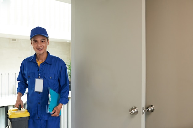 Free photo cheerful asian handyman arriving on house call