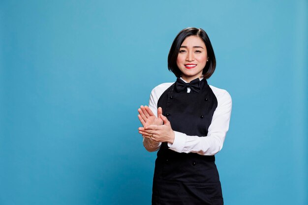 Foto gratuita allegra cameriera asiatica che applaude e guarda la macchina fotografica con espressione felice. la receptionist sorridente e gioiosa della donna fa applausi, congratulandosi e celebrando il ritratto di successo