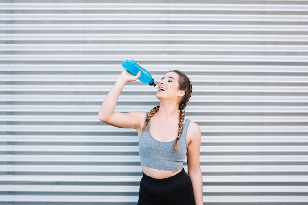 Cheerful athletic woman having blue drink