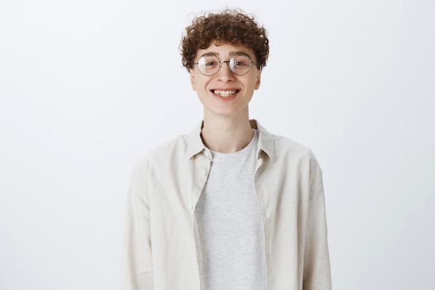 Free photo cheerful attractive teenage guy posing against the white wall