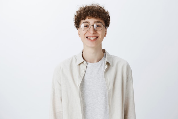 Cheerful attractive teenage guy posing against the white wall