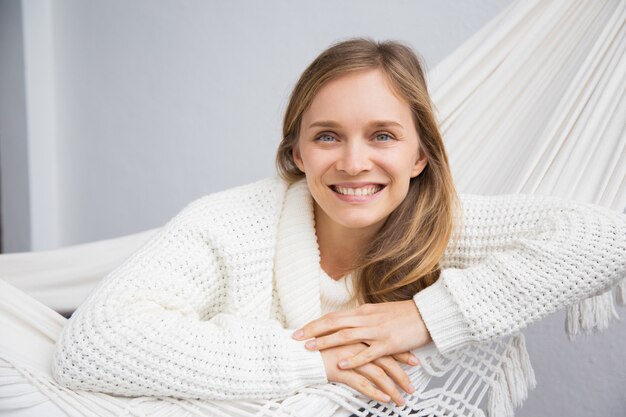 Cheerful attractive young woman in white sweater relaxing