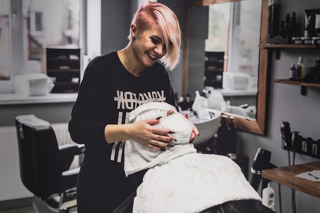 Cheerful barber and client in towel