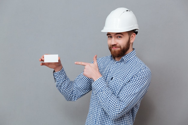 Cheerful bearded builder holding blank business card