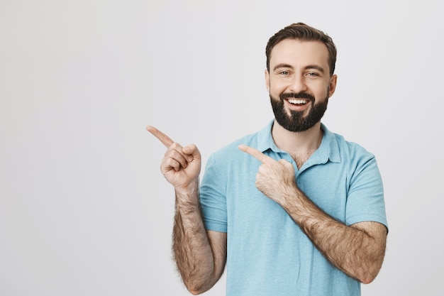 Free photo cheerful bearded guy pointing upper left corner