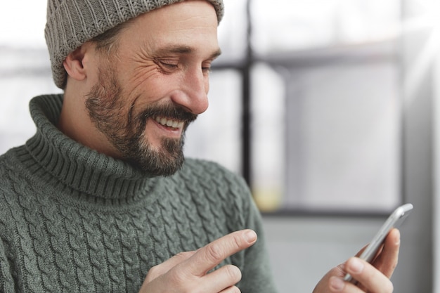 Cheerful bearded man wearing knitted warm sweater and hat