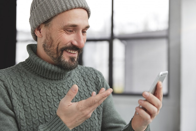 Free photo cheerful bearded man wearing knitted warm sweater and hat