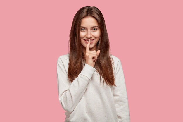 cheerful beautiful brunette posing against the pink wall