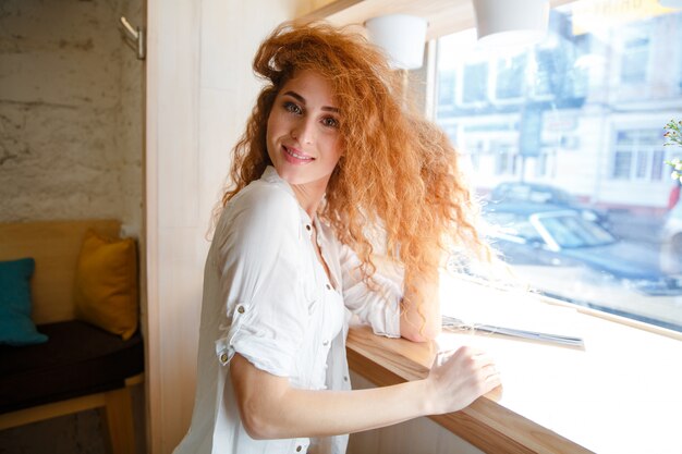 Cheerful beautiful redhead young lady sitting in cafe