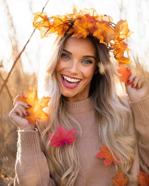 Cheerful beautiful woman wearing maple leaves wreath having fun at outdoors