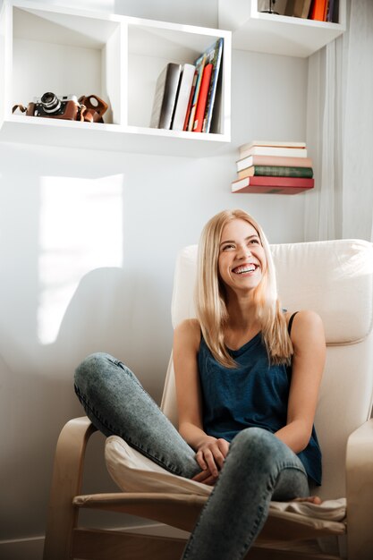 Cheerful beautiful young woman sitting in chair at home