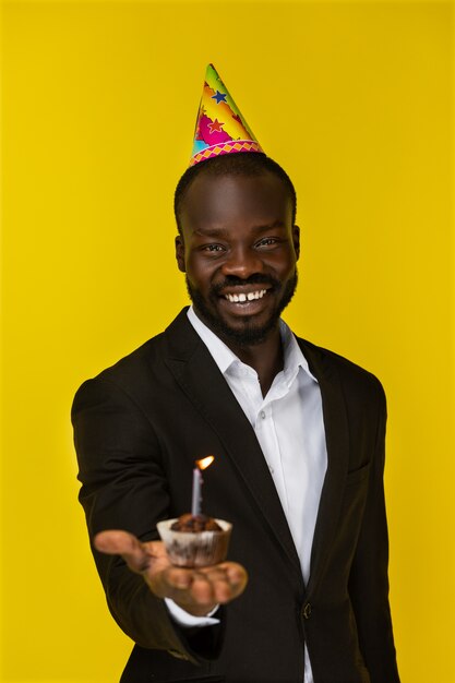 Cheerful black man holding birthday cupcake