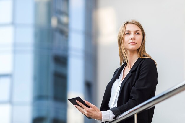 Cheerful blonde with tablet looking away