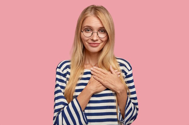 Cheerful blonde woman posing against the pink wall