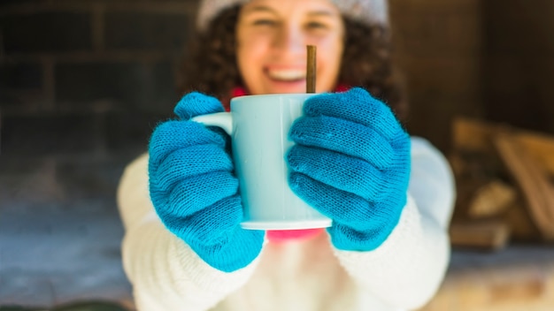 Cheerful blurred woman showing hot beverage