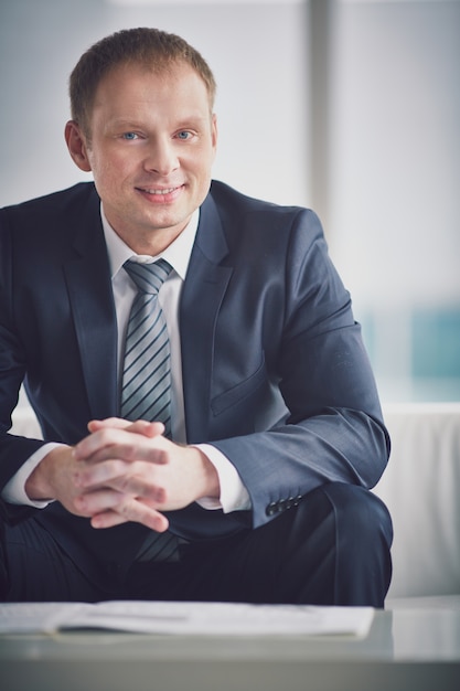 Free photo cheerful boss sitting with a newspaper on the table