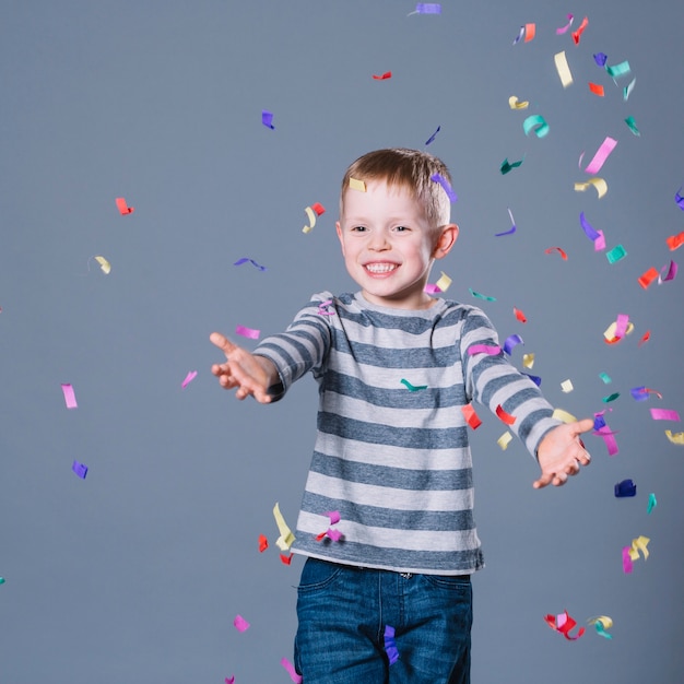 Free photo cheerful boy catching confetti