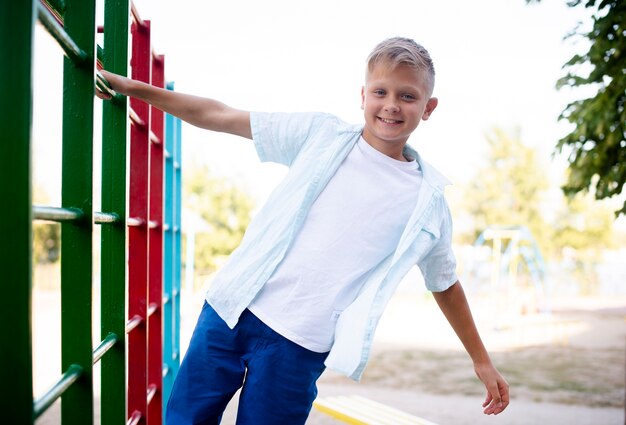 Cheerful boy clinging to the pipe with one hand