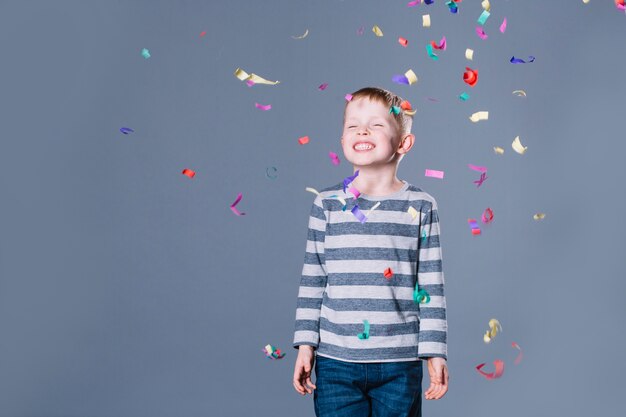 Cheerful boy under confetti