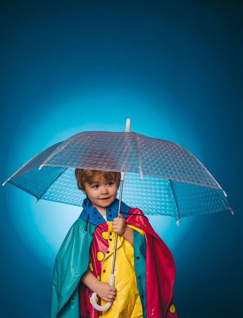 Cheerful boy in raincoat with colorful umbrella. cute little child boy are getting ready for autumn. kid in rain. sale for entire autumn collection, incredible discounts and wonderful choice.