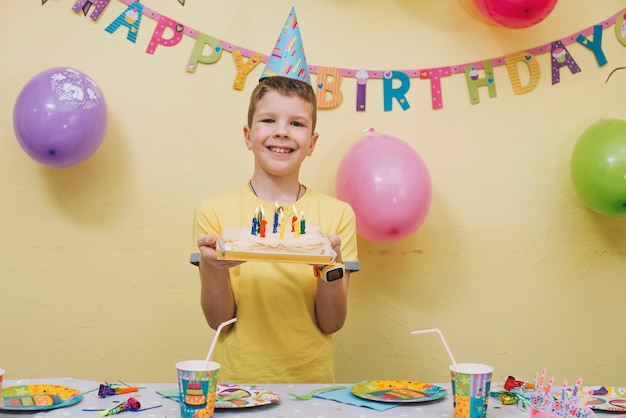 誕生日のケーキを持つ陽気な少年