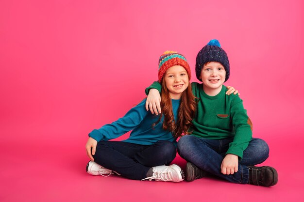 Cheerful brother and sister hugging and looking camera