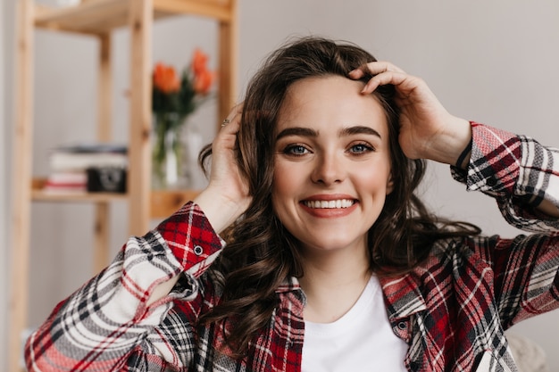 Cheerful brunette woman in good mood looks into front and smiles widely