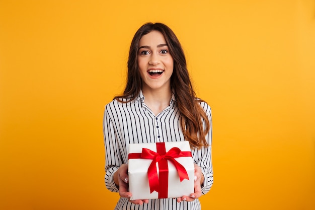 cheerful brunette woman in shirt holding gift box