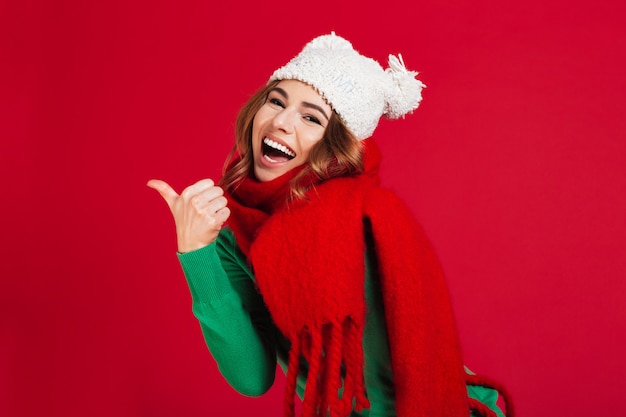 Cheerful brunette woman in sweater, funny hat and scarf