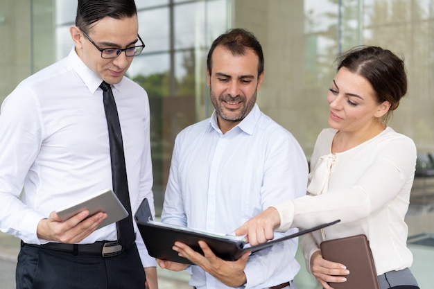 Cheerful business executives analyzing chart in folder