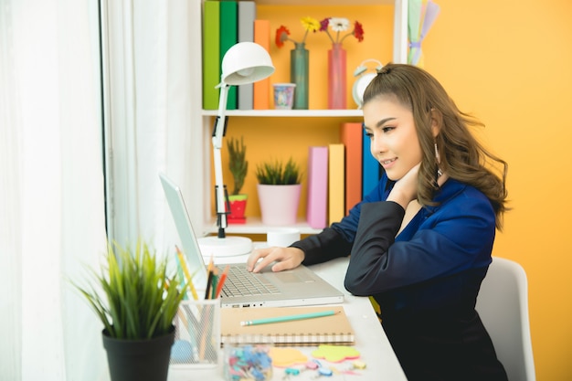 Cheerful business lady working on laptop in office