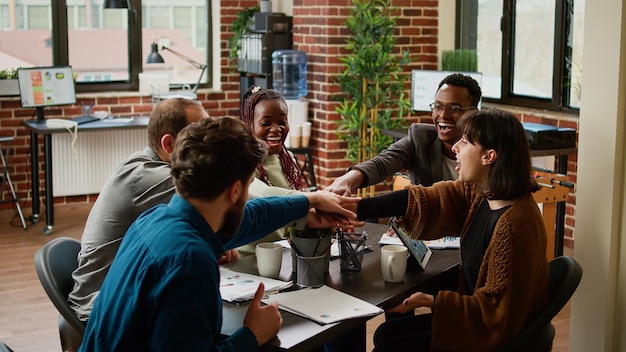 Cheerful business people celebrating successful partnership, feeling happy about presentastion success. Smiling coworkers enjoying collaboration agreement, teamwork in boardroom.