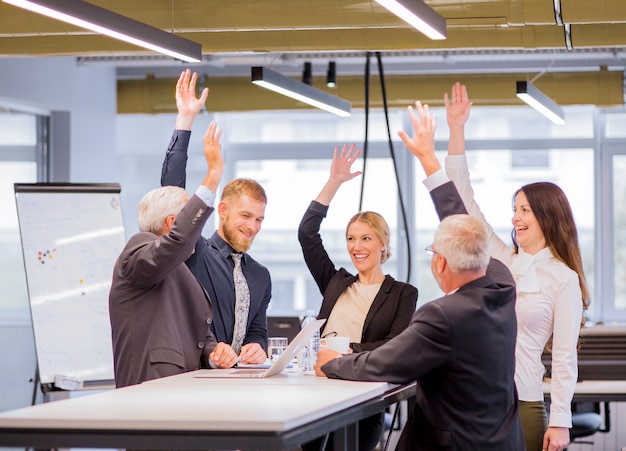 Cheerful business people in the meeting raising the arms