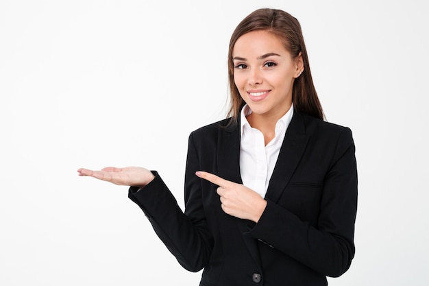 Free photo cheerful business woman pointing to copyspace.