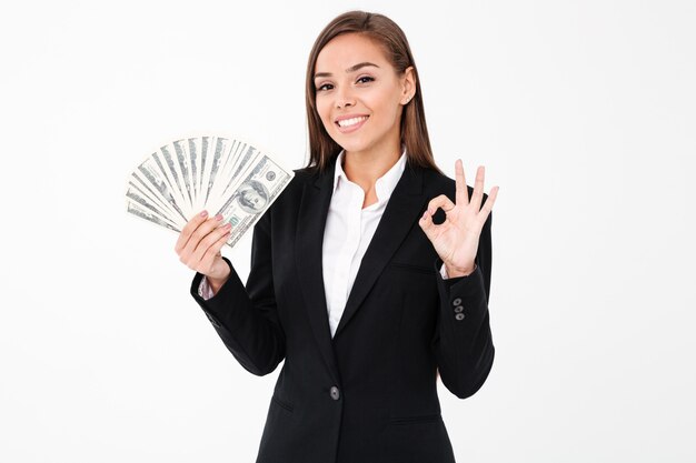 Cheerful business woman showing okay gesture holding money