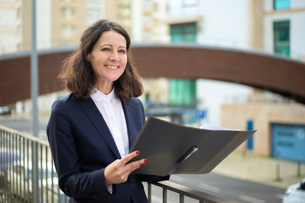 Cheerful businesswoman holding folder