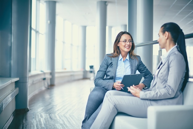 Cheerful businesswoman talking to her workmate