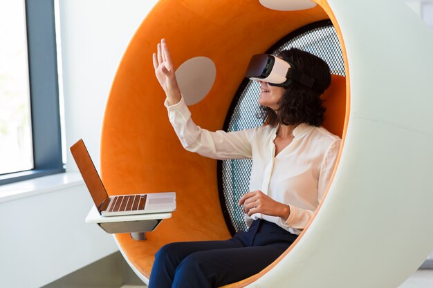 Cheerful businesswoman with laptop watching virtual presentation