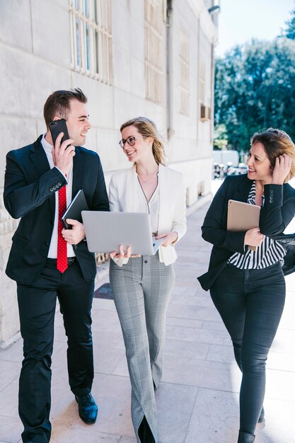 Cheerful businesswomen and businessman using technologies