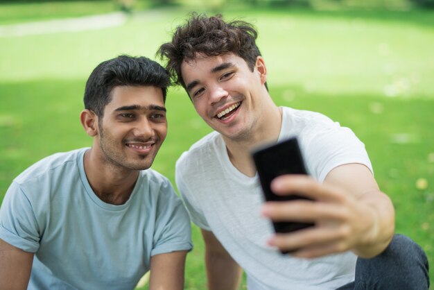 Cheerful carefree young men taking selfie on phone