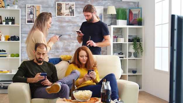 쾌활한 백인 친구들이 거실에 있는 큰 TV에서 비디오 게임을 하고 있습니다.