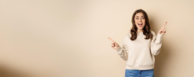 Free photo cheerful caucasian woman showing directions two ways pointing sideways at variants choices for custo