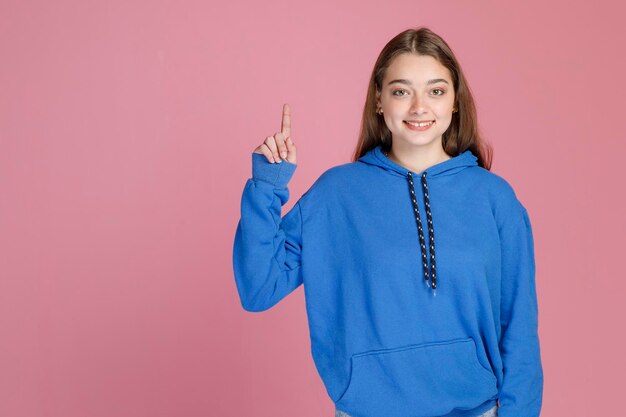 Cheerful caucasian woman with fair hair pointing up with index finger giving correct direction