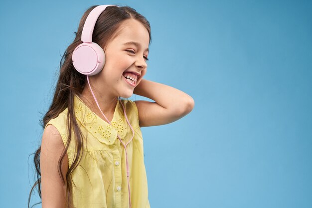 Cheerful child in pink headphones smiling and posing.