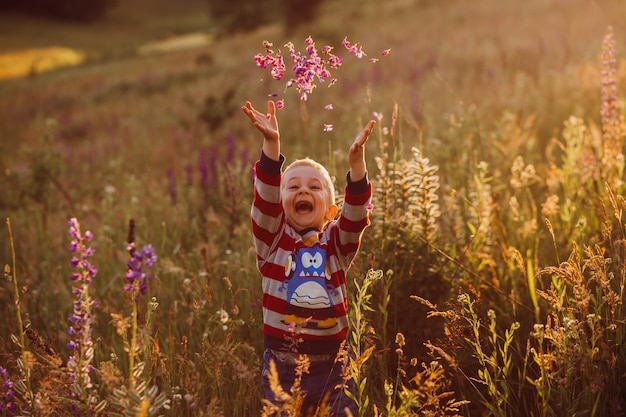 Бесплатное фото Веселый ребенок бросает лепестки на позирование на поле лавандер